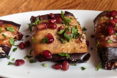 Patlıcan rulosu, fındık ve peynirle doldurulmuş, nar tohumlarıyla süslenmiş. Vejetaryen yemeği.