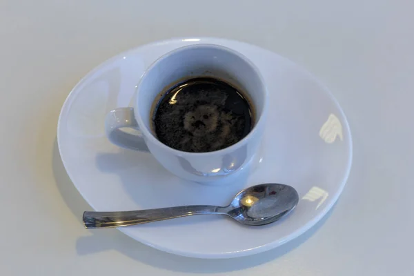 Black coffee in a white cup on white background. Nobody, isolated.