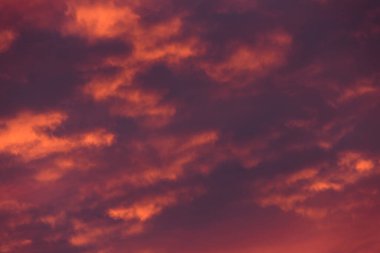 Fırtınalı bulutlar ve kıpkırmızı gün batımı. Akşam bulutlarında mor bir parıltı. Arka plan olarak gökyüzü desenleri.