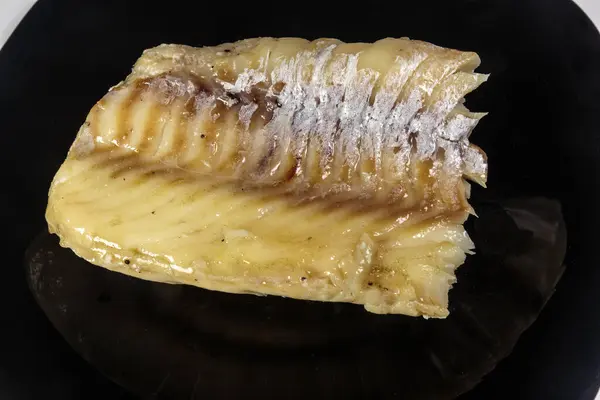 Siyah bir tabakta haşlanmış morina balığı. Beslenme yemeği. Lezzetli.