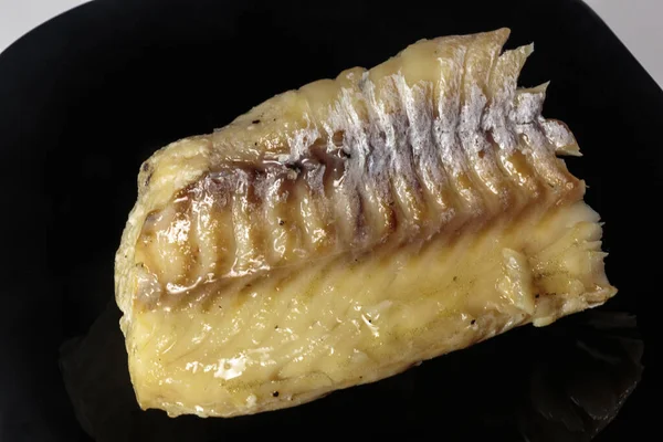 Siyah bir tabakta haşlanmış morina balığı. Beslenme yemeği. Lezzetli.