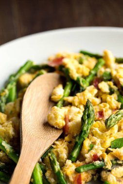 Kuşkonmaz ve jambonlu omlet. Beyaz tabakta ve tahta kaşıkla