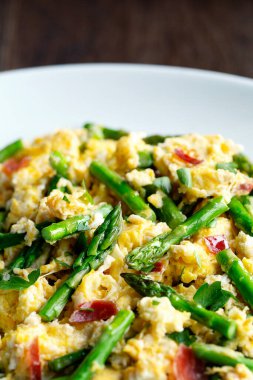 Kuşkonmaz ve İspanyol jambonu ile çırpılmış yumurta. Beyaz tabak ahşap arka planda.