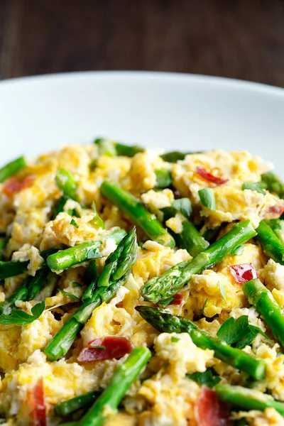 Kuşkonmaz ve İspanyol jambonu ile çırpılmış yumurta. Beyaz tabak ahşap arka planda.