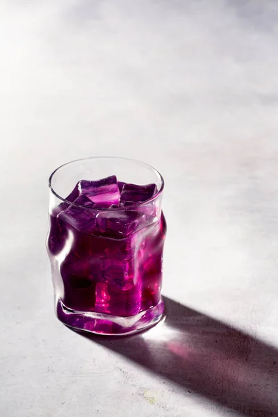 Curved glass tumbler with purple liquid and back light