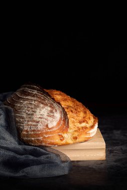 Ahşap tahtada kırsal ekmek ve koyu arkaplanda gri renkte gazlı bez.
