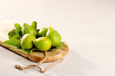 Yapraklarda beş incir ve beyaz arka planda ahşap tahta.