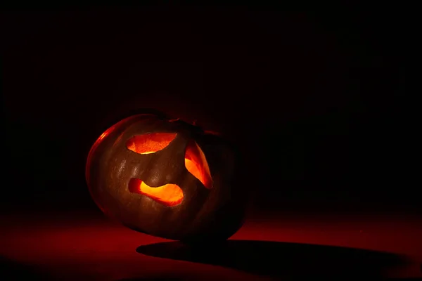 Иллюминированная Тыква Хэллоуин Наклонным Дьявольским Лицом Темном Фоне Красных Тонах — стоковое фото