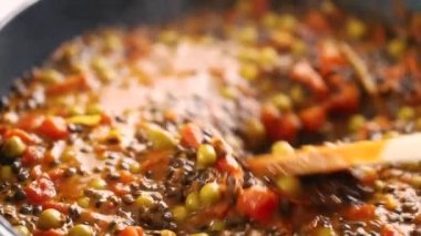 Kaynamış siyah mercimek köri, ahşap kaşık karıştırma