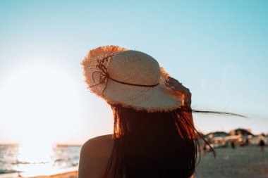 Sahilde denize bakan bir kız, gün batımı.