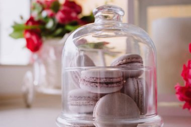 Pembe Fransız macarons ahşap kurullarında, yumuşak odak arka plan cam altında
