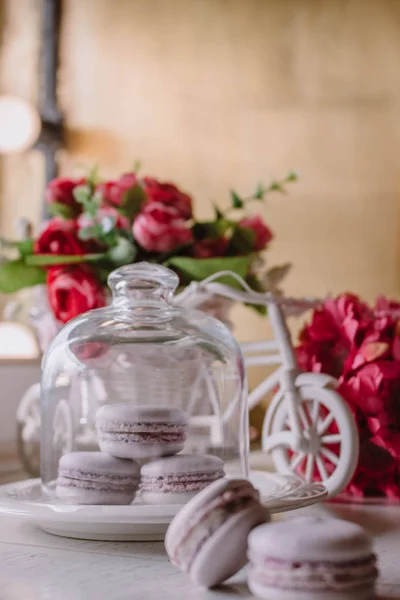 Macarons français roses sous le verre sur les planches en bois, fond soft focus. Sweet desert Dans le café local . — Photo