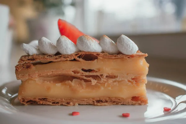 El postre clásico francés millefeuille en una tabla de madera. Pastel de Napoleón en bandeja o mesa con cardamon, menta y una taza de café y decoración de flores en el fondo. Vista de cerca En el acogedor ca local —  Fotos de Stock