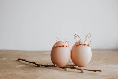 Ahşap arka plan üzerinde söğüt dalı ve tavşan kulakları ile beyaz yumurta Demet