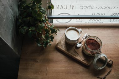 Kahve kapuçino ile cam fincan tiramisu yüksek açı görünümü. Vegsn dükkanında, yerel rahat kafede. Ahşap arka plan, samimi tarzı. Kopyalama alanı