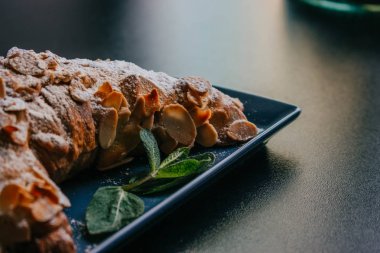 Koyu bir arka plan üzerinde tabakta pudra şekeri ve nane ile lezzetli kruvasan