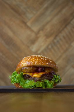 Burger, kıyma pirzisi ile hamburger sandviç, eritilmiş peynir, meyve kiraz ve armut. Ahşap zemin ve hafif ahşap tahta üzerinde yan görünüm.