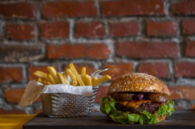 Tuğla duvar arka plan izole ahşap masa üzerinde sepet içinde armut ve kiraz ve patates kızartması ile Craft sığır burger.