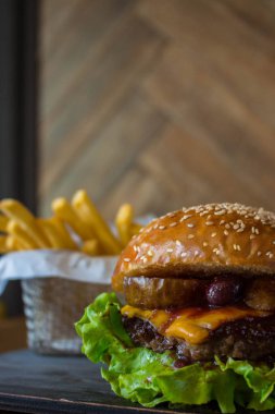 Ahşap duvar arka plan izole ahşap masa üzerinde sepet içinde armut ve kiraz ve patates kızartması ile Craft sığır burger.