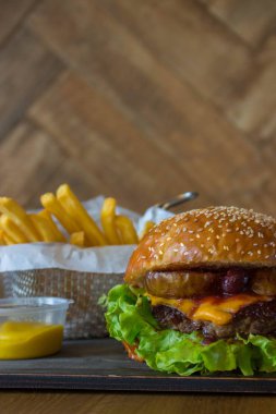 Ahşap duvar arka plan izole ahşap masa üzerinde sepet içinde armut ve kiraz ve patates kızartması ile Craft sığır burger.