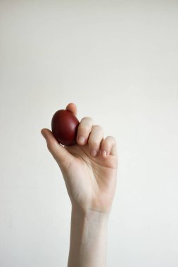 Tanınmayan kadınlar bir yumurtayı tutarlar. Kırmızı bir Paskalya yumurtası devirmek. Eski tatil geleneği. Beyaz arka planda izole edilmiş. Metin boş alan. Mutlu Paskalya!