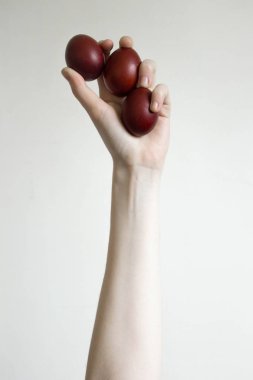 Tanınmayan kadınlar üç yumurta tutarlar. Kırmızı bir Paskalya yumurtası devirmek. Eski tatil geleneği. Beyaz arka planda izole edilmiş. Metin boş alan. Mutlu Paskalya!