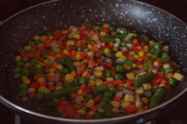 Siyah tavada kızarmış sebze karışımı. Tavada dilimlenmiş sebzeler. Dondurulmuş vegan kahvaltı hazırlığı.