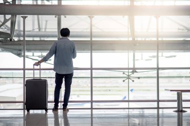 Küçük Asya bavul bagaj ile ayakta adam ve smartphone uluslararası havaalanının terminal, holding seyahat yaşam tarzı kavramı