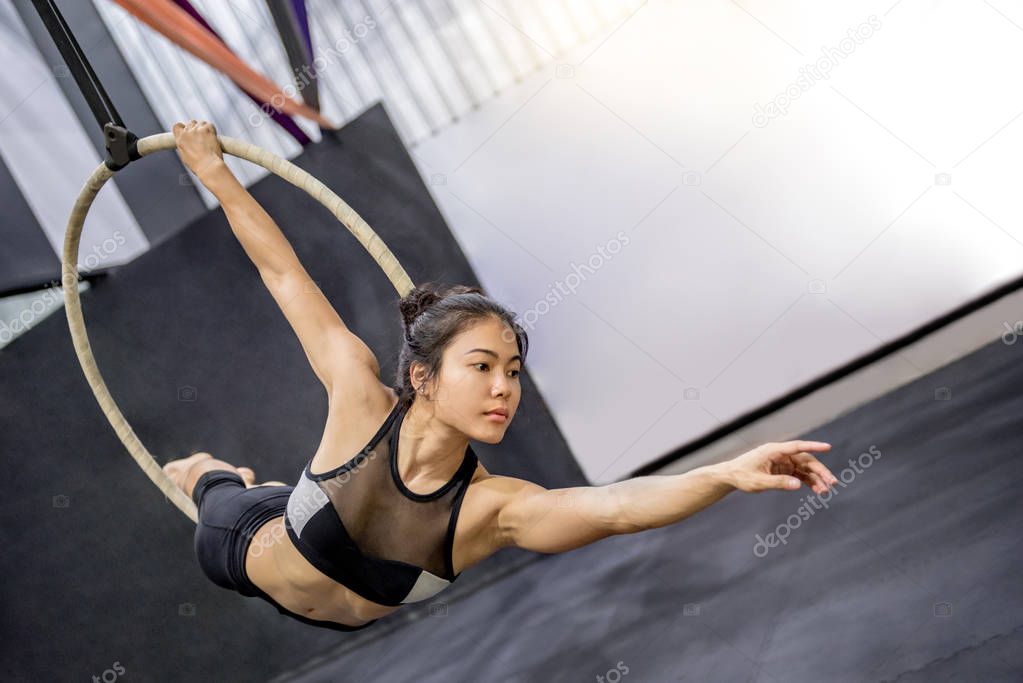 young asian acrobatic woman doing her gymnastics performance on aerial hoop or aerial ring