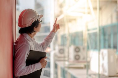Genç Asyalı mühendis veya dosyaları tutan ve inşaat alanında koruyucu ekipman kask giyen süre işaret mimar. Mühendislik, Mimarlık ve inşaat iş kavramları