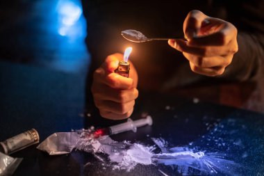 Erkek keş el erime, enjeksiyon için şırınga için kaşık ve çakmak kullanarak eroin doz hazırlanıyor. Sert uyuşturucu aşırı doz ve bağımlılık kavramı
