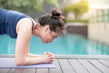 Yüzme havuzu yanında Yoga egzersiz yaparak Genç Asyalı çekici kadın. Pilates Egzersiz ve sağlıklı yaşam kavramları. Uluslararası yoga gün