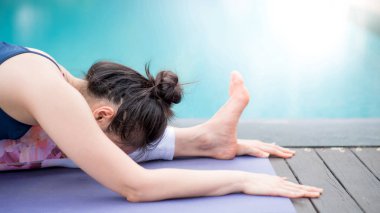Yüzme havuzu yanında Yoga egzersiz yaparak Genç Asyalı çekici kadın. Pilates Egzersiz ve sağlıklı yaşam kavramları. Uluslararası yoga gün