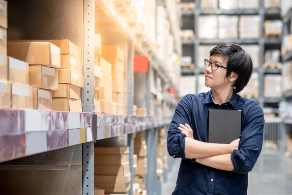 Genç Asyalı adam stocktaking ürünün depoda raf karton kutu, dijital tablet kullanarak yapıyor. fiziksel envanter sayım kavramı