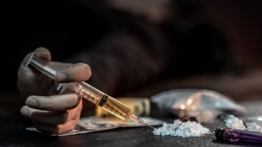 Erkek keş el eroin toz, kaşık ve çakmak eroin pişirme ve para karanlık yere yakın yalan sırasında uyuşturucu iğne şırınga tutarak. Sert uyuşturucu bağımlılığı kavramı