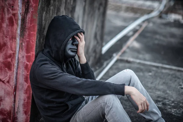 Siyah maske hoody giyiyor içinde gizemli adam ceket terk edilmiş binada yorgun hissediyorum, kendini imha intihar bağımlılığı veya majör depresif bozukluk kavramları oturan