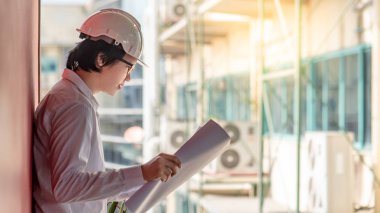 Mühendis veya mimar inşaat alanında bir kişisel koruyucu ekipman kask giyen süre mimari çizimi kontrol. Mühendislik, Mimarlık ve inşaat iş kavramları