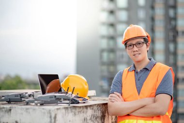 Küçük Asya mühendislik dron laptop ve smartphone ile inşaat alanında çalışan adam. İnsansız hava aracı (İHA) arazi için kullanarak ve inşaat mühendisliği proje sitesi anket oluşturma.