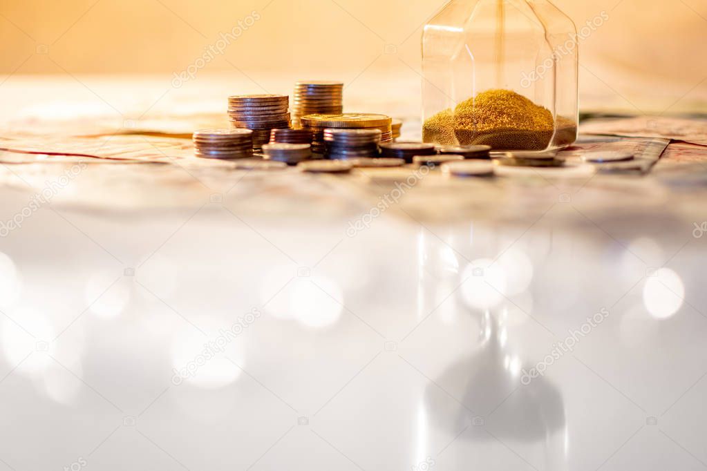 Reflection of brown sand running through the shape of modern hourglass on glowing table with currency. Time investment and passing time. Urgency countdown timer for business deadline concept