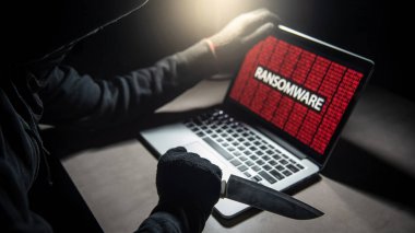 Erkek hacker dizüstü bilgisayar ekranında kırmızı dijital ikili ransomware uyarı ile gösterilen bıçak ile iş parçacığı. Siber saldırı ve Internet veri güvenlik kavramı