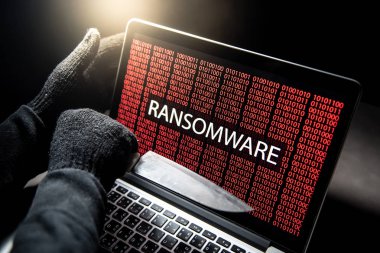 Erkek hacker dizüstü bilgisayar ekranında kırmızı dijital ikili ransomware uyarı ile gösterilen bıçak ile iş parçacığı. Siber saldırı ve Internet veri güvenlik kavramı