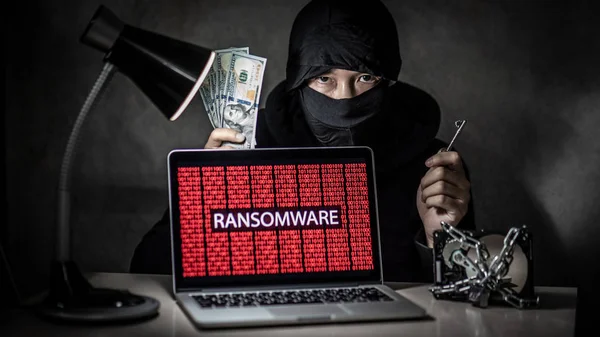 男性黑客持有钥匙和美元钞票与笔记本电脑屏幕显示红色二进制勒索攻击硬盘驱动器锁定 网络攻击与网络数据安全概念 — 图库照片