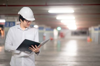 Genç Asyalı erkek mühendis veya mimar holding inşaat sahasında kırmızı merdiven üzerinde giyiyor koruyucu güvenlik kask dosyaları. İnşaat Mühendisliği, Mimarlık ve inşaat kavramı bina