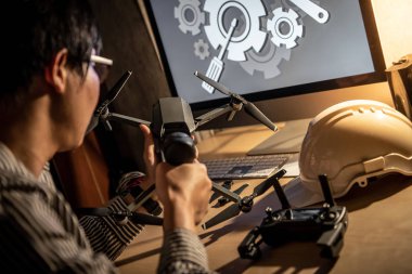 Asya teknik mühendis dron bilgisayar ve araçları üstünde okul sırası ile onarmak için elektrikli tornavida kullanarak. Erkek teknisyen sabitleme veya bakım dron. İnsansız hava aracı (İHA) fotoğraf kavramı