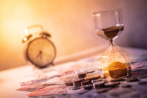 沙子贯穿在桌子上的沙漏形状上 纸币和硬币的国际货币 时间投资和退休储蓄 紧急倒计时计时器的业务期限概念 — 图库照片