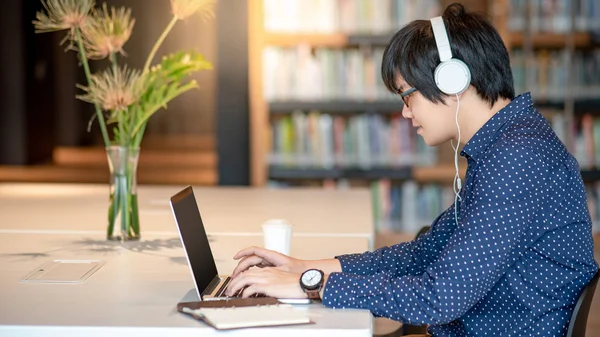 Jovem Asiático Trabalhando Com Computador Portátil Ouvindo Música Biblioteca Pública — Fotografia de Stock