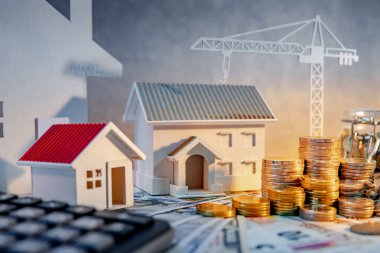 Gayrimenkul veya emlak geliştirme. İnşaat iş yatırım kavramı. Ev ipotek kredi oranı. Hesap makinesi, ev ve vinç ile uluslararası banknot para yığını masaya modelleri.