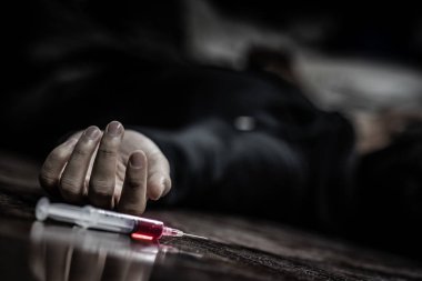 Junkie man lying on the floor near drug injection syringe. Death from drug overdose and addiction concept clipart