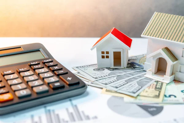 Real estate or property development. Construction business investment concept. Home mortgage loan rate. House models on international banknotes with calculator on the table.