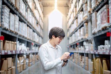 Genç Asyalı adam alışveriş kontrol listesi ambar toptan, ürün arayan depolama kavramı alışveriş